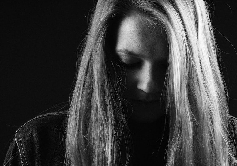 Black and white photo of a sad girl thinking we need to talk about suicide