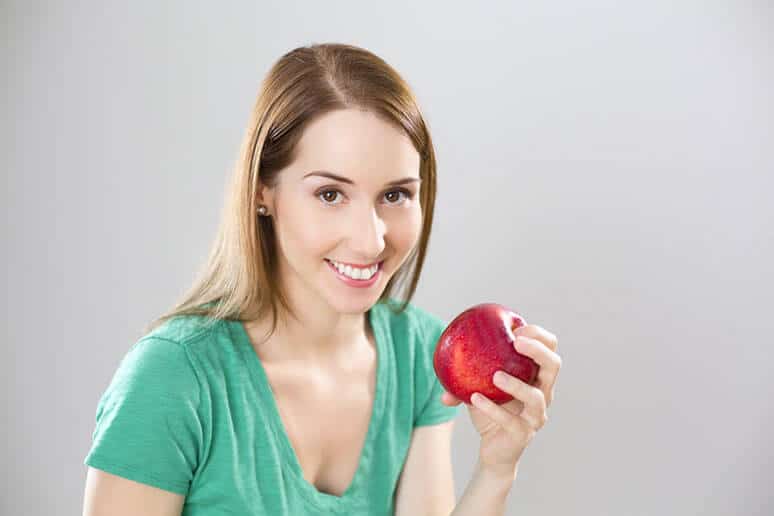 A dietitian smiles while holding an apple